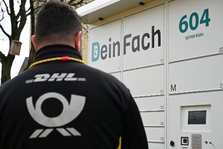Ein DHL-Paketbote holt Sendungen aus einem DeinFach-Automaten.