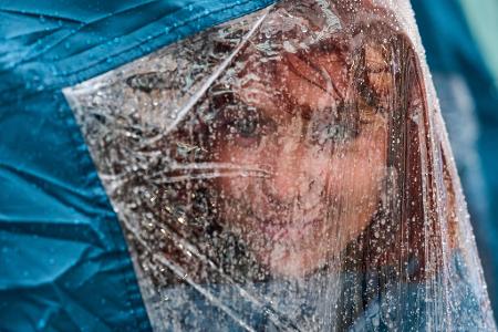 Eine Aktivistin blickt unter ihrer Regenkappe hervor, während sie bei starkem Regen auf dem Platz Puerta del Sol in Madrid an einem Protestcamp für das Recht auf Wohnen teilnimmt.