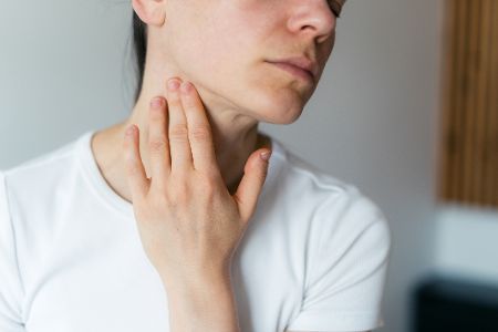 Frau tastet nach Lymphknoten am Hals