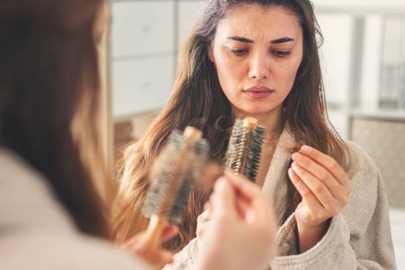 Junge Frau betrachtet Haare in einer Bürste