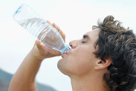 Junger Mann trinkt durstig aus einer Wasserflasche