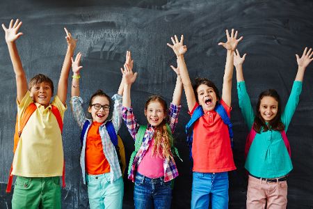 Gruppe von Schulkindern vor einer Tafel jubelt begeistert