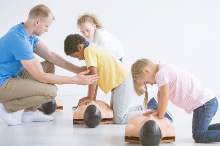 Kinder üben Herzdruckmassagen an Puppen