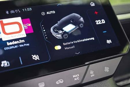 Die Aufnahme zeigt das zentrale Infotainment-Display des Jeep Compass Elektro im Innenraum. Auf dem Touchscreen sind Radio-Kacheln sowie das EV-Menü mit Batterie‑Vorklimatisierung, Temperaturanzeige (22,0 °C) und Lüftungssteuerung zu sehen. Die Szene verdeutlicht die Bedienung von Klimatisierung und Batteriemanagement im elektrischen Kompakt‑SUV.