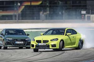 Das Foto zeigt einen Audi RS3 Competition Limited und einen BMW M2 Coupe auf dem Hockenheimring. Der gelbgrüne BMW driftet mit starkem Reifenqualm durch eine Kurve, während der dunkelgrüne Audi auf der Ideallinie folgt. Aufnahmeort laut IPTC ist Hockenheim.