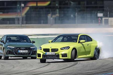 Das Foto zeigt einen Audi RS3 Competition Limited und einen BMW M2 Coupe auf dem Hockenheimring. Der gelbgrüne BMW driftet mit starkem Reifenqualm durch eine Kurve, während der dunkelgrüne Audi auf der Ideallinie folgt. Aufnahmeort laut IPTC ist Hockenheim.