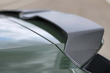 Die Detailaufnahme zeigt den Heckspoiler des Audi RS3 Competition Limited. Der aus Karbonfaser gefertigte Spoiler sitzt auf der Heckklappe; die sichtbare Carbonstruktur und der schwarze Einsatz betonen die aerodynamische Ausführung auf dem in Dunkelgrün lackierten Fahrzeug.
