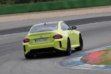 Das Foto zeigt ein BMW M2 Coupe auf dem Hockenheimring in Hockenheim. Die Heckansicht in Kurvenfahrt offenbart typische M-Merkmale wie breiten Stand, schwarzen Heckdiffusor und eine Vierrohr-Auspuffanlage; der Wagen ist in auffälligem Grün mit schwarzem Dach und Felgen lackiert.