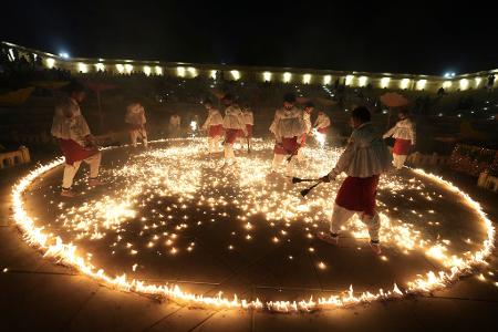 Menschen in traditioneller Tracht führen während der neuntägigen Feierlichkeiten des hinduistischen Festes Navratri in Ahmedabad in Indien den „Mashal Raas“ auf.