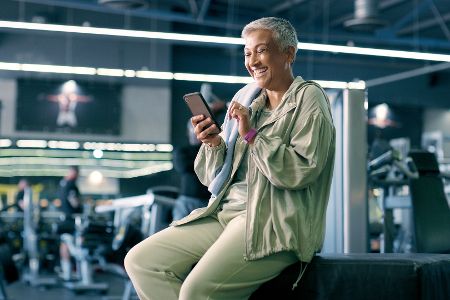Ältere Frau telefoniert im Fitnessstudio