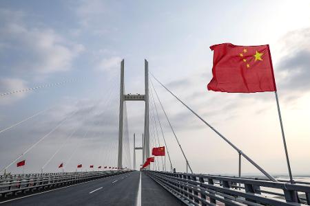 Chinesische Fahnen wehen auf einer Brücke.