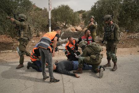 Palästinensische Sanitäter und ein israelischer Soldat kümmern sich um einen palästinensischen Mann, der von israelischen Soldaten angeschossen wurde.
