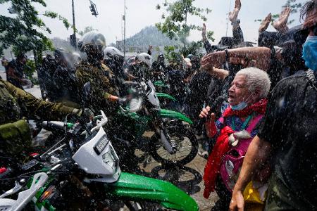 Die Polizei setzt während eines Marsches anlässlich des 7. Jahrestags des sozialen Aufstands in Chile im Jahr 2019 einen Wasserwerfer ein, um Demonstranten zu vertreiben, die gegen geplante Ausgabenkürzungen der Regierung protestieren.