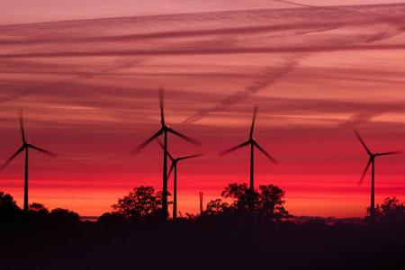 Die Rotoren von Windkraftanlagen drehen sich kurz nach Sonnenuntergang in einem Windpark in Mecklenburg-Vorpommern.