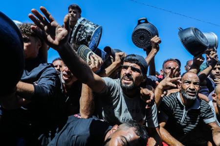 Palästinenser stehen dicht gedrängt, um Lebensmittelhilfe entgegenzunehmen, die von Hilfsorganisationen im Stadtteil Al-Mawasi in Chan Junis verteilt wird.