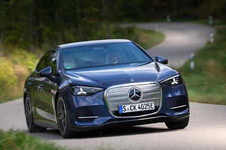 Das Foto zeigt einen Mercedes C400 4MATIC in Frontansicht. Die C‑Klasse‑Limousine fährt auf einer kurvigen Landstraße; sichtbar sind der zentrale Mercedes‑Stern, der geschlossene Grillbereich und LED‑Scheinwerfer. Die Szene zeigt das Fahrzeug in Fahrt auf der Straße.