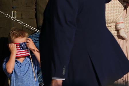 Ein Junge verdeckt sein Gesicht mit einer amerikanischen Flagge.