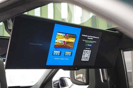 Die Aufnahme zeigt das Fond‑Infotainment des BMW 740 xDrive mit einem großformatigen Bildschirm hinter den Vordersitzen. Auf dem Display ist die AirConsole‑Gaming‑Oberfläche mit QR‑Code zur Smartphone‑Kopplung als Controller zu sehen. Die Perspektive aus dem Fond verdeutlicht die Rear‑Seat‑Entertainment‑Ausstattung der Luxuslimousine.