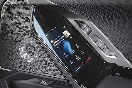 Das Foto zeigt die Bedieneinheit an der Beifahrertür eines BMW 740 xDrive. Sichtbar sind ein integriertes Touchscreen-Bedienfeld für Medien‑, Klima‑ und Komfortfunktionen, Verriegelungstasten sowie eine dekorative Lautsprecherabdeckung des Bowers & Wilkins Soundsystems in der Türverkleidung.