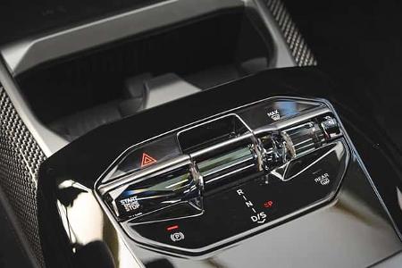 Die Detailaufnahme zeigt die Mittelkonsole eines BMW 740 xDrive mit elektronischem Automatikwählhebel und zentraler Bedieneinheit. Sichtbar sind Start‑Engine‑Stop‑Taste, Warnblinktaste, Bedienelemente für Lüftung und Heckscheibenheizung, die Schaltstufen R‑N‑D/S sowie die elektrische Parkbremse.