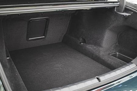 Das Foto zeigt den Kofferraum eines BMW 740 xDrive aus der 7er-Baureihe. Sichtbar sind die vollständig mit Teppich verkleidete Ladefläche, eine Skidurchreiche in der Rückwand, ein seitliches Staufach sowie Verzurrpunkte und eine breite Ladeöffnung. Es handelt sich um die xDrive-Variante mit Allradantrieb; die Abbildung fokussiert ausschließlich den Gepäckraum.