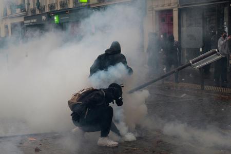 Ein Demonstrant hebt bei Protesten in Paris ein Tränengasgeschoss auf.