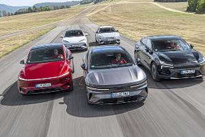 Die Aufnahme zeigt einen Fahrvergleich aktueller Elektro-Modelle: Kia EV6 GT AWD, BYD Sealion 7 EXcellence AWD, Polestar 4 Dual Motor, Tesla Model Y Performance und Zeekr 7GT AWD. Die Fahrzeuge fahren nebeneinander in Frontansicht auf einer breiten Asphaltstrecke in ländlicher Umgebung; betont werden die aerodynamischen Silhouetten, durchgehenden LED-Lichtbänder und der Allradantrieb der Modelle. Das Bild stammt laut Dateiname vom 16.09.2026.