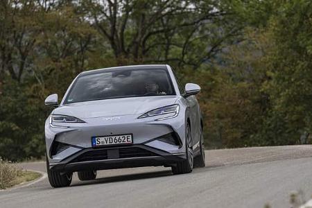 Das Foto zeigt den BYD Sealion 7 EXcellence AWD in Frontansicht auf einer Landstraße. Der SUV mit Allradantrieb (AWD) trägt schmale LED-Scheinwerfer und das BYD-Logo auf der Fronthaube; ein deutsches E‑Kennzeichen ist sichtbar, die Aufnahme erfolgt im Fahrbetrieb in bewaldeter Umgebung.