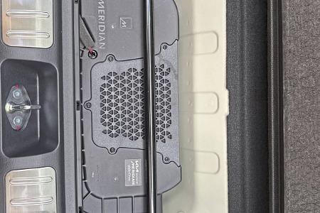 Die Aufnahme zeigt die Kofferraumstrebe im Heck des Kia EV6 GT unter dem Laderaumboden. Die quer verlaufende, verschraubte Metallstrebe verbindet die Karosserie-Aufnahmepunkte zur Versteifung; daneben ist ein Modul des Meridian‑Soundsystems im Unterflurfach sichtbar. Perspektive von oben in den geöffneten Kofferraum mit Fokus auf Befestigungspunkte und Bauteilanordnung.