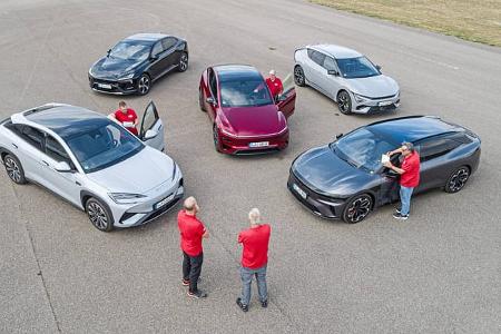Das Foto zeigt fünf Elektrofahrzeuge der Marken BYD, Kia, Polestar, Tesla und Zeekr: Kia EV 6 GT AWD, BYD Sealion 7 EXcellence AWD, Polestar 4 Dual Motor, Tesla Model Y Performance und Zeekr 7GT AWD, die auf einer abgesperrten Fahrbahn kreisförmig angeordnet sind. Mehrere Tester stehen bei den Fahrzeugen, was auf einen Vergleichstest aktueller Allrad‑Performance‑Crossover/SUV hindeutet.
