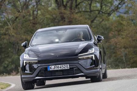 Das Foto zeigt einen Polestar 4 Dual Motor in Frontansicht auf einer kurvigen Landstraße. Die Dual‑Motor‑Variante setzt auf zwei Elektromotoren für Allradantrieb; markant sind die schmalen LED-Leuchten und das geschlossene Frontdesign eines Elektrofahrzeugs.
