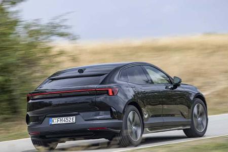 Das Foto zeigt einen Polestar 4 Dual Motor in der Heckansicht auf einer Landstraße. Das batterieelektrische SUV‑Coupé mit Dual‑Motor‑Allradantrieb ist mit durchgehendem Rücklichtband und fließender Dachlinie zu sehen. Die Aufnahme entsteht in Fahrt in ländlicher Umgebung.