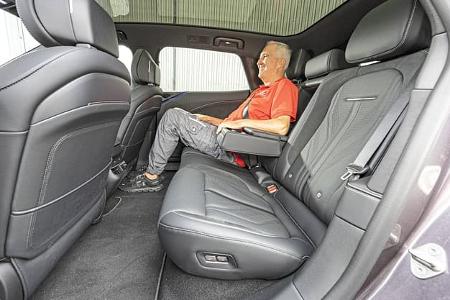 Das Foto zeigt den Fond des Zeekr 7 GT AWD; eine Person sitzt hinten auf der Rückbank mit heruntergeklappter Mittelarmlehne. Die schwarzen Sitze mit Kontrastnähten und integrierten Kopfstützen bieten sichtbar viel Beinfreiheit, hinter der Mittelkonsole sind Luftausströmer und Bedienelemente für die Fondklimatisierung zu erkennen. Die Bezeichnung AWD im Dateinamen weist auf die Allradvariante des Modells hin.