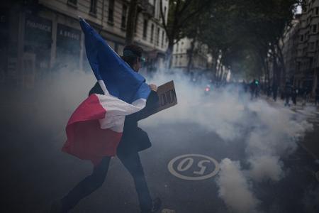 Ein Demonstrant hält während einer Demonstration in Lyon gegen steigende Lebenshaltungskosten eine französische Flagge.