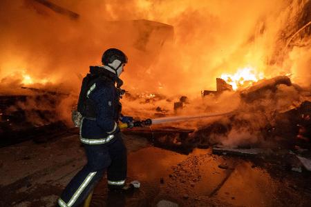 Vor den Flammen: Ein Feuerwehrmann löscht nach dem russischen Luftangriff einen Brand in einem Wohngebiet.