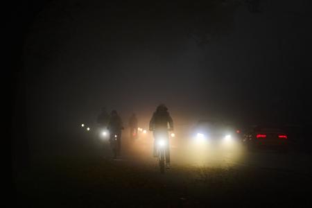 Rad- und Autofahrer fahren am frühen Morgen im Nebel über den Osterdeich.